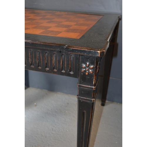 478 - An Empire style ebonised games table, with rotating marquetry chess top, raised on square tapered le... 