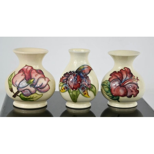 14 - Three Moorcroft vases, two in the Magnolia pattern, one limited edition 75/94, and another in the Ir... 