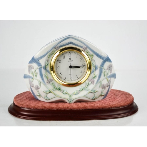 141 - A Lladro porcelain clock with wooden stand, 13cm high.