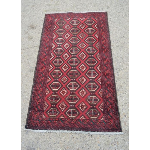 561 - A red ground rug with diamond shape pattern, 98cm by 178cm