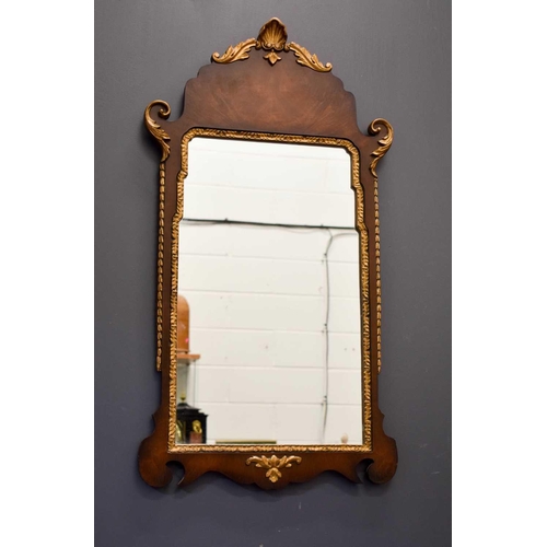 411 - A reproduction mahogany and gold painted wall mirror, with shell and foliate scroll carved detailing... 