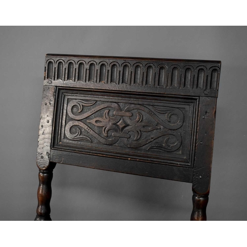 493 - An 18th century oak chair, the back panel carved with nulled top rail, raised on turned legs and bob... 