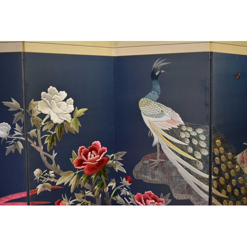 503 - A 20th century embroidered Chinese panel depicting peacock amidst flowers, on a dark blue ground, ea... 