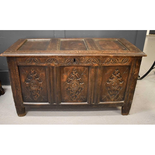 506 - An 18th century oak coffer, with triple panelled lid and front, carved with diamonds, raised on stil... 