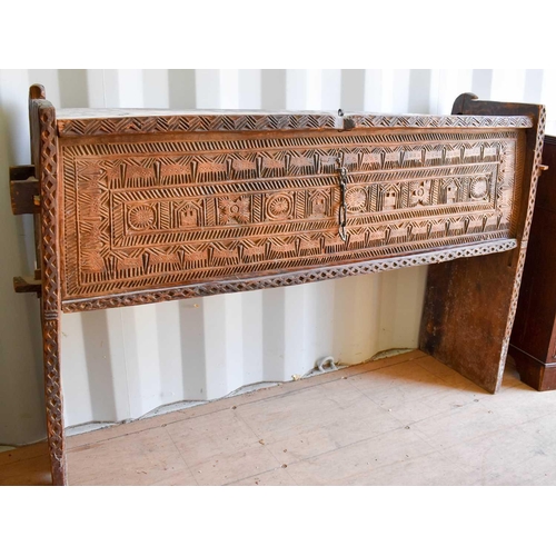 507 - A boarded wooden chest, raised on tall end boards, the top and front carved with decoration, 95cms t... 