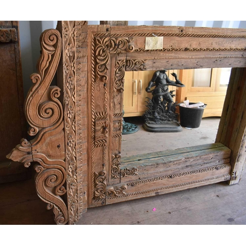 512 - A large wooden window frame, made into a mirror, with a twin scroll pediment, 116cms tall by 110cms ... 