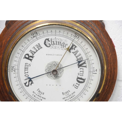 14 - A Victorian carved oak cased aneroid barometer, signed Beasley and Son, 92cms tall