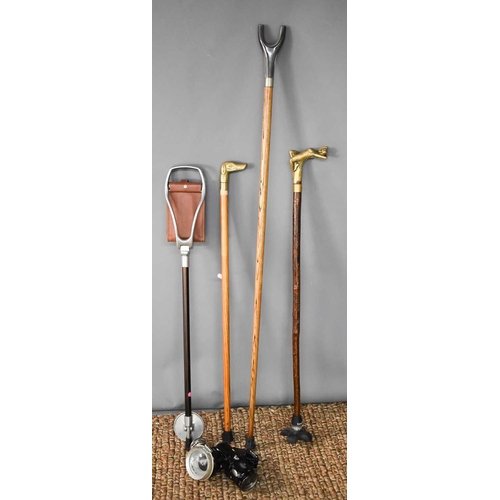 147 - A vintage shooting stick, crook, and two brass handled walking canes; one in the form of a dog head,... 