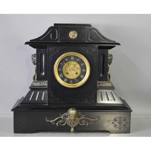 22 - An antique slate mantle clock, with visible escapement, twin hoop and female face mask handles, blac... 