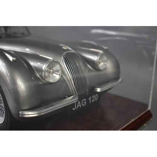 376 - A model silver Jaguar, with numberplate JAG120, in a perspex case.