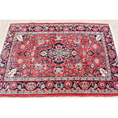 430 - A Persian wool rug with red ground, the central motif bordered by flowers and having a border of sty... 