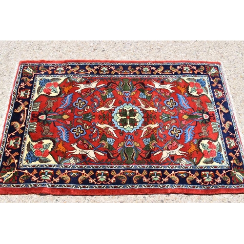 436 - A fine Middle Eastern wool rug, hand woven in deep pile, the red ground centre depicting birds, deer... 