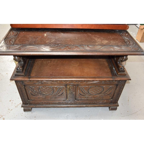 472 - An oak monks bench/ box settle with carved decoration to the front and top and having lion form arms... 