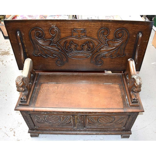 472 - An oak monks bench/ box settle with carved decoration to the front and top and having lion form arms... 