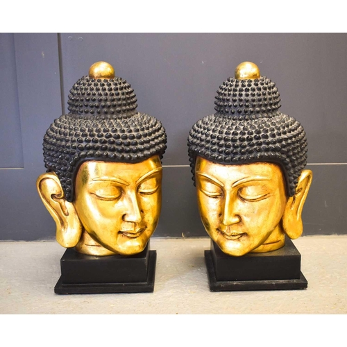 477 - A pair of 20th century Buddha heads, with gilded faces, raised on square plinths, 56cm high.