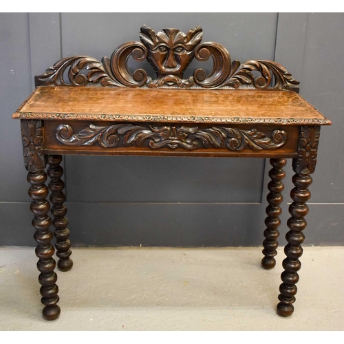 483 - An oak 1930s silver table, the carved back depicting a face mask and scrollwork, with a frieze drawe... 