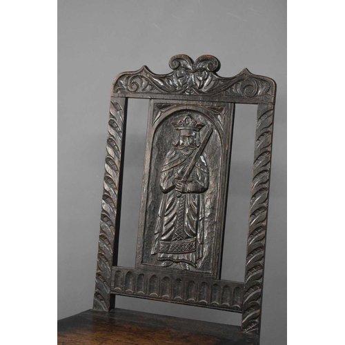 492 - A late 18th/early 19th century hall chair, the back panel carved with a saint.