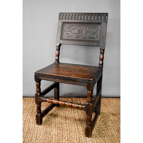 493 - An 18th century oak chair, the back panel carved with nulled top rail, raised on turned legs and bob... 