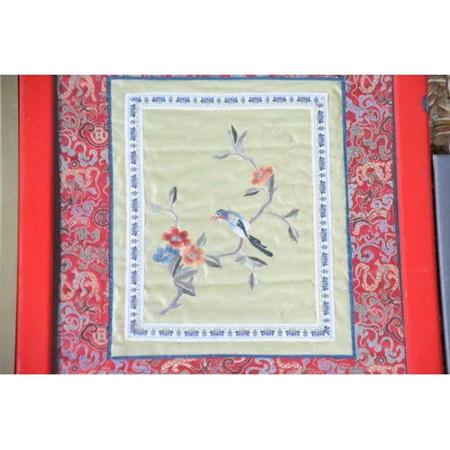 140 - A group of four framed and glazed Chinese embroidered silk panels of birds among bamboo and others.