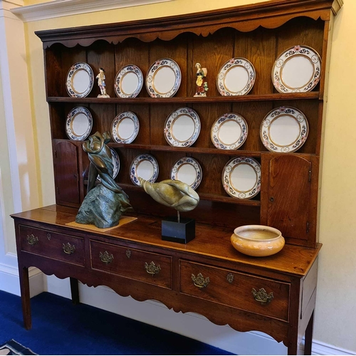 535 - An 18th century oak Welsh dresser, the plate rack with shaped cornice and wavy frieze, over three sh... 