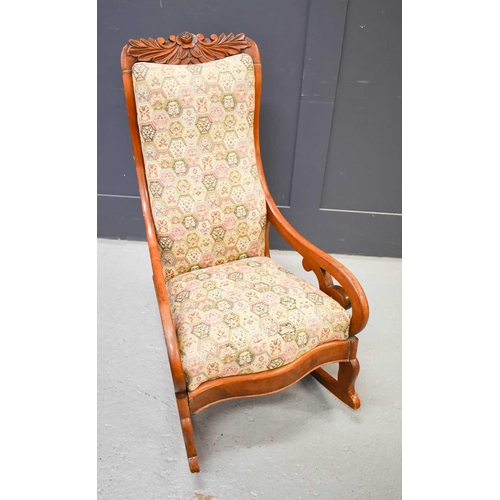 536 - An American rocking chair with carved leaf and flower design to the top.