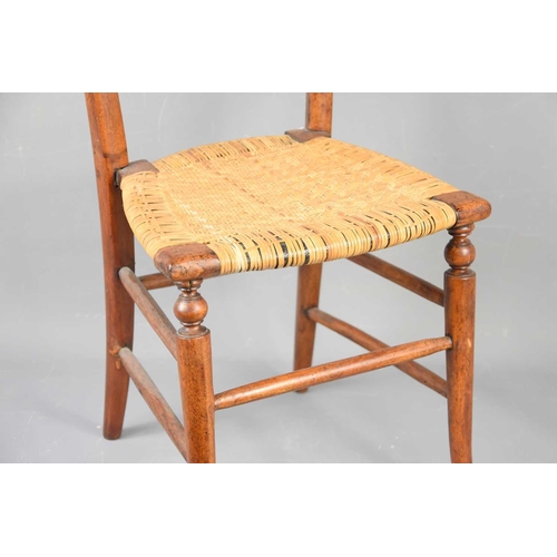 555 - A 19th century rush seated childs chair, with outswept legs.