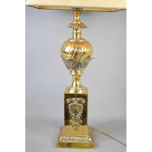 595 - An antique brass lamp base, embossed with decoration, with cream shade, 95cm to the top of shade.