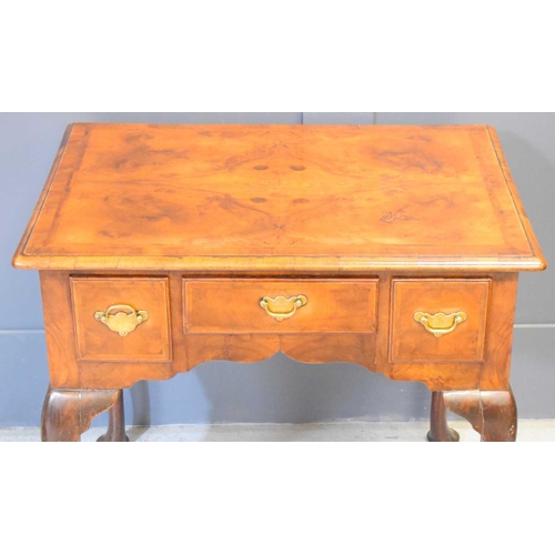 607 - A George III burr walnut lowboy, with quarter veneered top above three frieze drawers, raised on cab... 