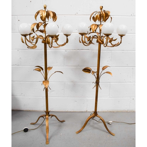 613 - A pair of 20th century gilt-metal floor lamps, with leaf decoration and spherical glass shades, on c... 