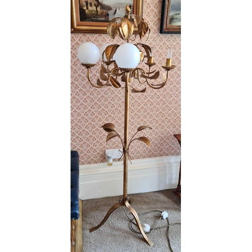 613 - A pair of 20th century gilt-metal floor lamps, with leaf decoration and spherical glass shades, on c... 