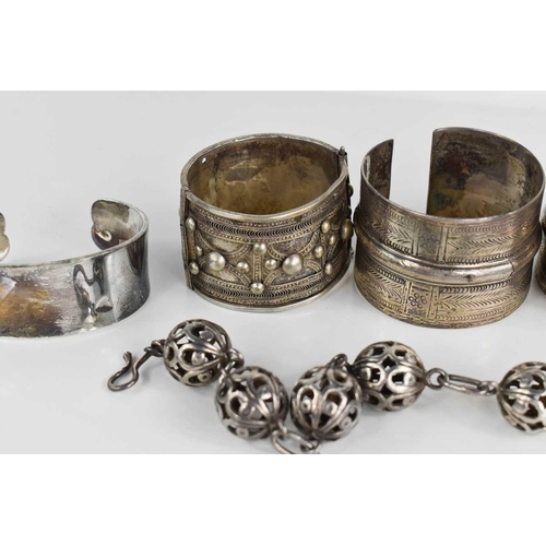 129 - A group of silver bangles to include an Art Nouveau amethyst set bangle, Indian examples, silver cha... 