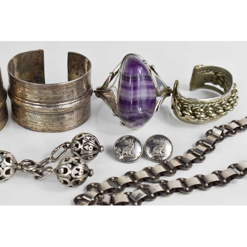 129 - A group of silver bangles to include an Art Nouveau amethyst set bangle, Indian examples, silver cha... 