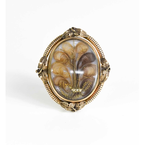 15 - A Victorian pinchbeck mourning brooch on stand, of oval form, inset with lockets of hair woven into ... 