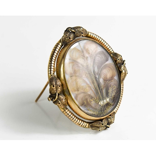 15 - A Victorian pinchbeck mourning brooch on stand, of oval form, inset with lockets of hair woven into ... 