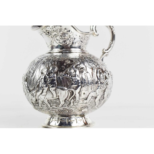 156 - A continental silver jug, embossed with putti in various poses, raised on a footed base, and having ... 