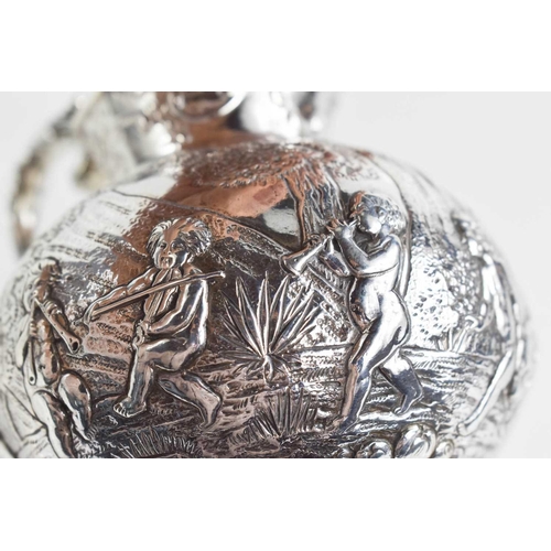 156 - A continental silver jug, embossed with putti in various poses, raised on a footed base, and having ... 