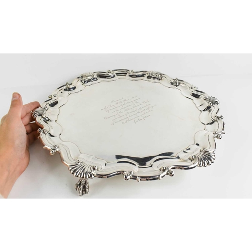 163 - A solid silver salver, Sheffield 1916, with scroll and shell decorated raised border, with three cla... 