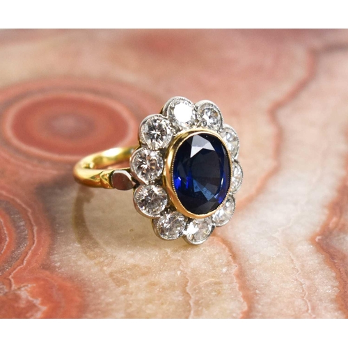 299 - An 18ct yellow gold, sapphire and diamond ring, the central oval cut deep cornflower blue sapphire o... 