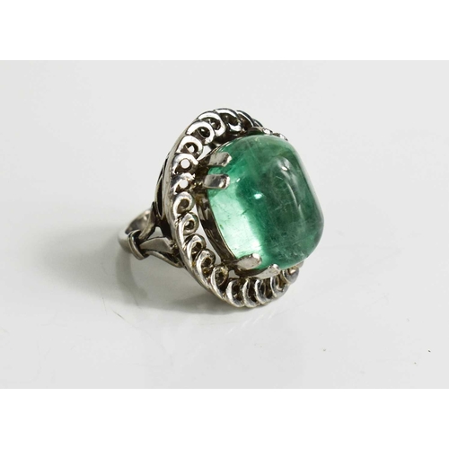 3 - An impressive 18ct white gold and boulder emerald ring, the stone bordered by decorative swirl borde... 