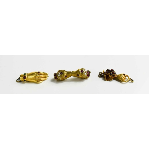 56 - Two gold (tested as) clasps in the form of hands, set with stones together with a gilt metal example... 