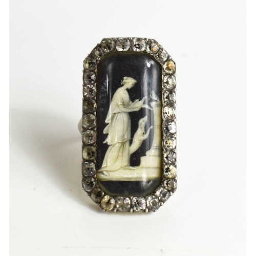 59 - A Victorian white metal and paste mourning ring with an enamelled centre depicting a woman beside do... 