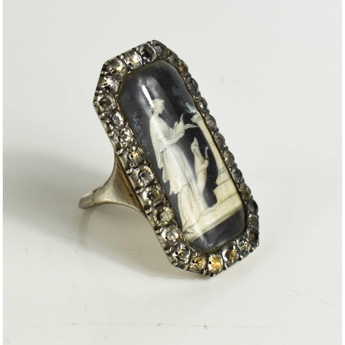 59 - A Victorian white metal and paste mourning ring with an enamelled centre depicting a woman beside do... 