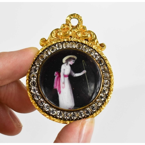 62 - A 19th century gilt metal and paste set pendant miniature, the enamelled centre depicting a lady hol... 