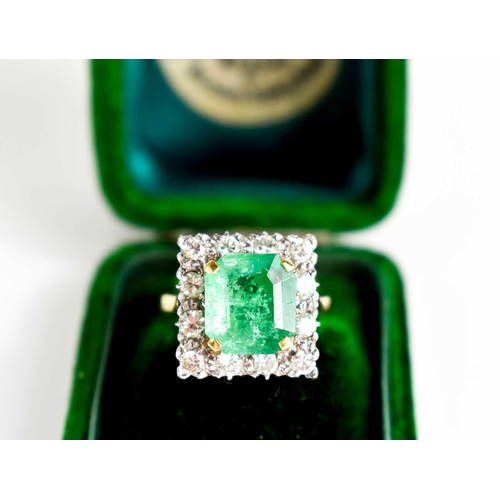 8 - An 18ct yellow gold, emerald and diamond ring, the cushion cut emerald bordered by twelve brilliant ... 