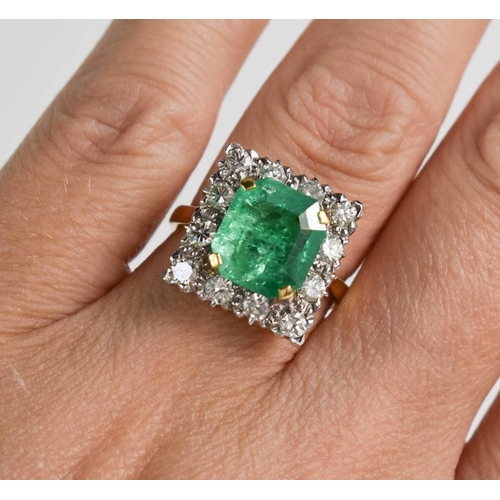 8 - An 18ct yellow gold, emerald and diamond ring, the cushion cut emerald bordered by twelve brilliant ... 