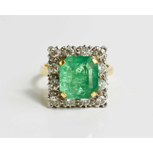 8 - An 18ct yellow gold, emerald and diamond ring, the cushion cut emerald bordered by twelve brilliant ... 