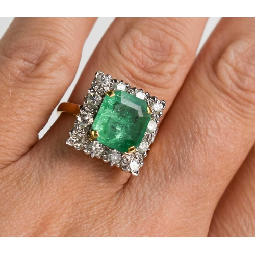 8 - An 18ct yellow gold, emerald and diamond ring, the cushion cut emerald bordered by twelve brilliant ... 