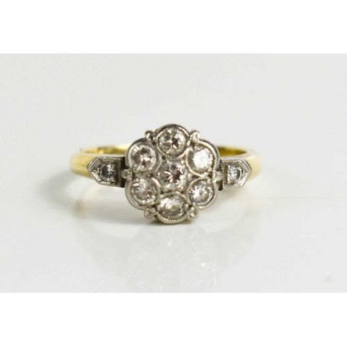 94 - An 18ct gold, platinum and diamond set flowerhead ring, set with seven brilliant cut diamonds to the... 