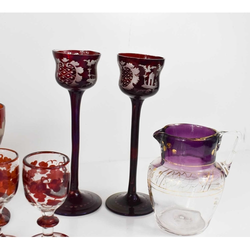 134 - A group of coloured bohemian glassware, to include pair of green and gilded bud vases, red painted g... 