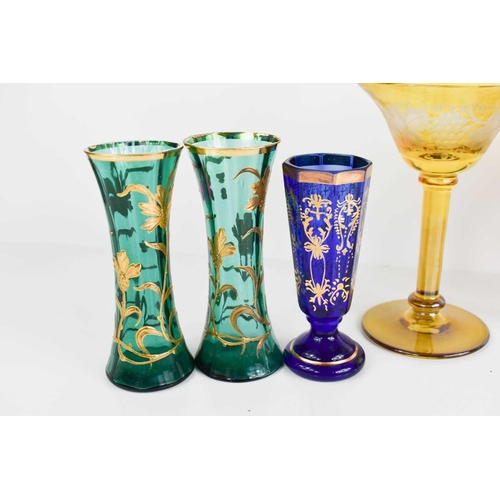 134 - A group of coloured bohemian glassware, to include pair of green and gilded bud vases, red painted g... 